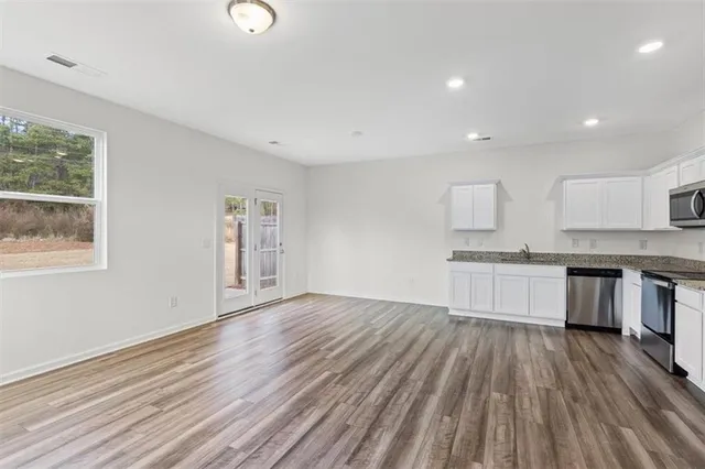 a open kitchen with white cabinets and wooden floor
