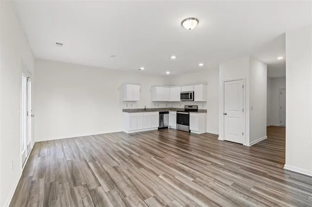 a view of kitchen with cabinets wooden floor and stainless steel appliances