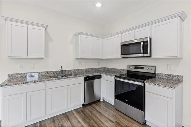 a kitchen with granite countertop white cabinets sink and stainless steel appliances