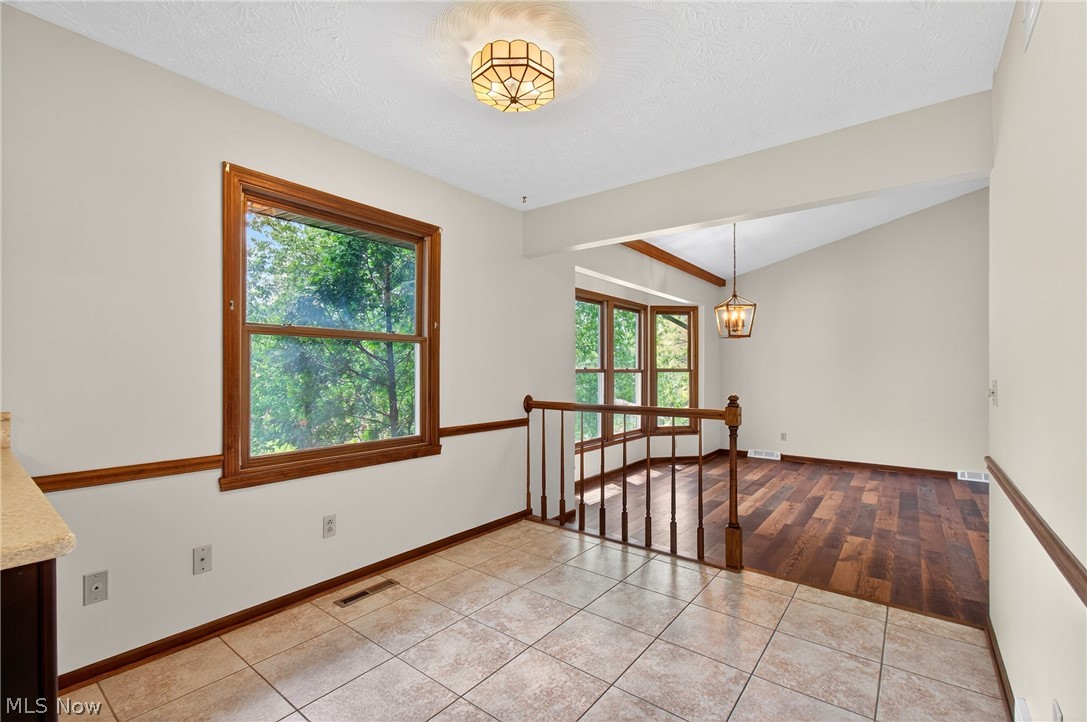 5346 Burlawn Street Northwest Canton, OH 44708 - Photo 9 of 40 Versatile interior space featuring tile flooring, a large window with natural wood trim, and a decorative ceiling light fixture