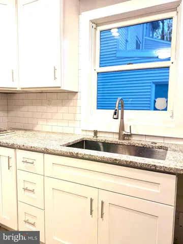 a kitchen with granite countertop white cabinets and a sink