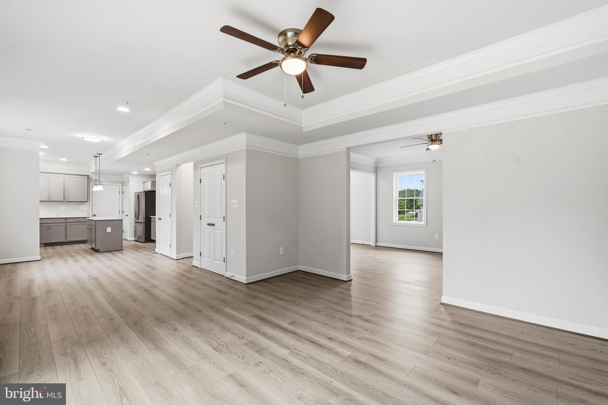 29725 Bruce Road Mechanicsville, MD 20659 - Photo 34 of 79 a view of an empty room and kitchen with wooden floor and a ceiling fan