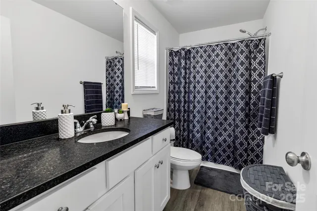 a bathroom with a granite countertop toilet a sink and a mirror