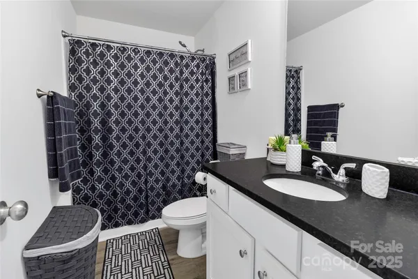 a bathroom with a granite countertop toilet a sink and a mirror