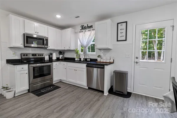 a kitchen with kitchen island granite countertop a stove a sink and a microwave