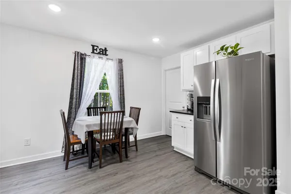 a kitchen with stainless steel appliances a dining table chairs and a refrigerator