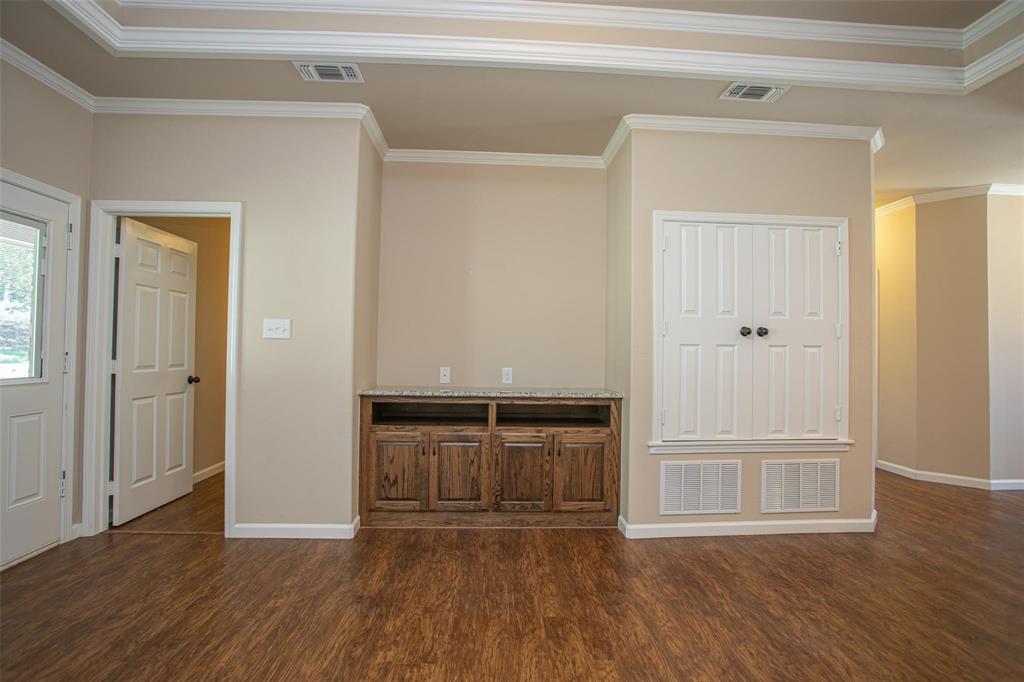 455 Neals Hill Road Oak Ridge, TX 76240 - Photo 9 of 19 Unfurnished living room featuring ornamental molding and dark wood-style flooring