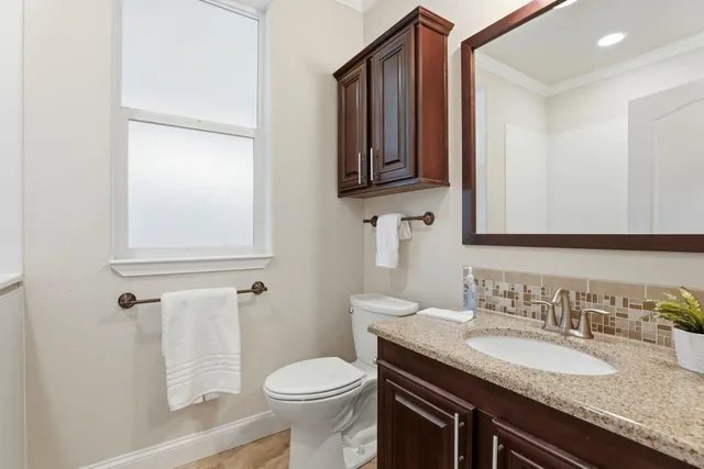 a bathroom with a granite countertop toilet sink and mirror