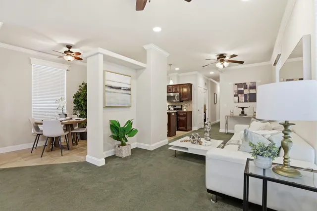 a living room with furniture potted plant a chandelier and a glass door