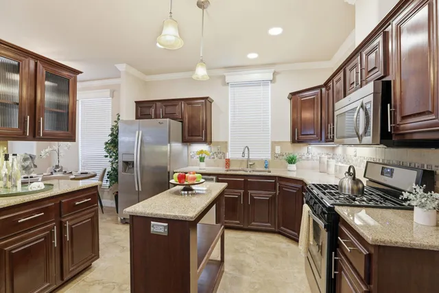 a kitchen with stainless steel appliances granite countertop a sink stove microwave and refrigerator