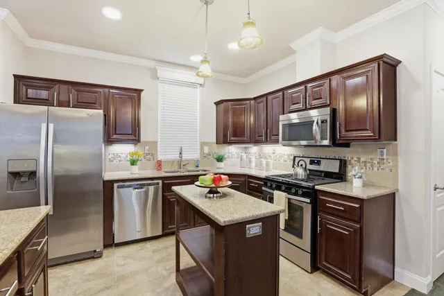 a kitchen with stainless steel appliances granite countertop a stove top oven a sink and a refrigerator