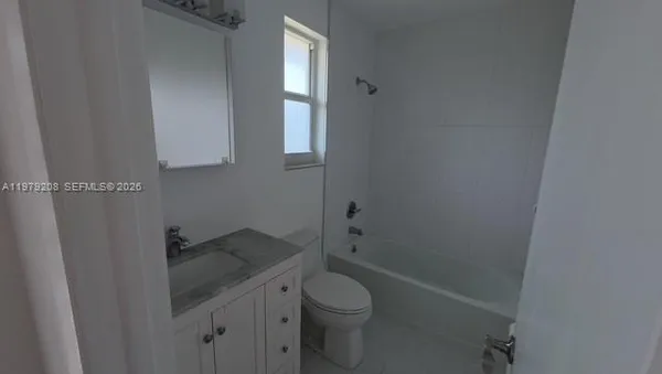 a bathroom with a granite countertop toilet and a sink