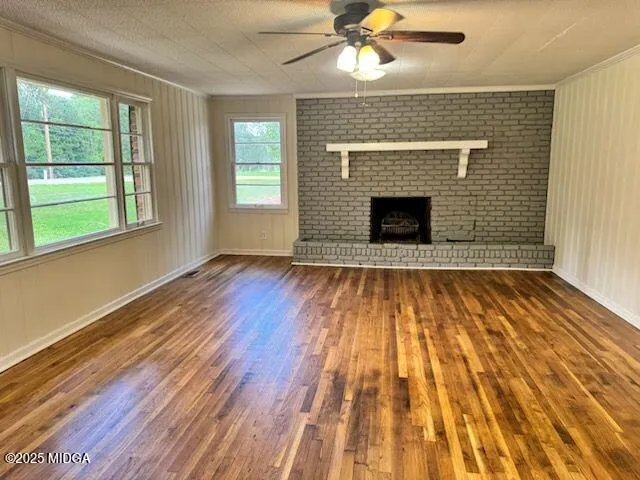 a view of an empty room with wooden floor fireplace and a window