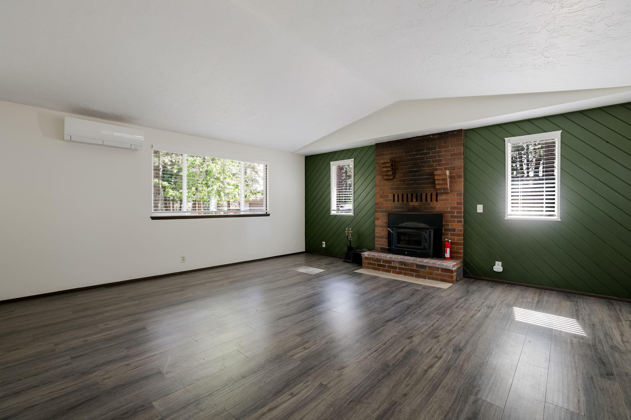 19968 Double Tree Court Bend, OR 97702 - Photo 3 of 28 an empty room with wooden floor a fireplace and windows