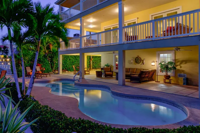 a view of a swimming pool with a yard and palm trees