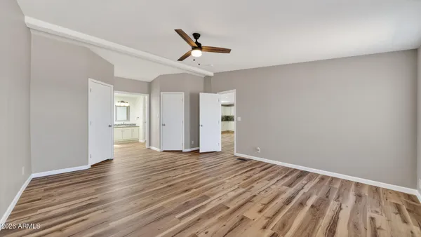 a view of empty room with wooden floor and fan