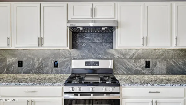 a kitchen with granite countertop white cabinets and a stove