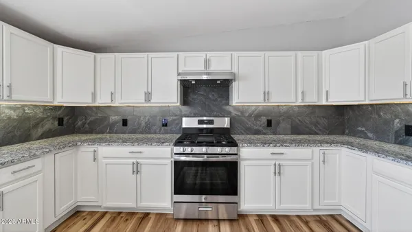 a kitchen with granite countertop white cabinets and appliances