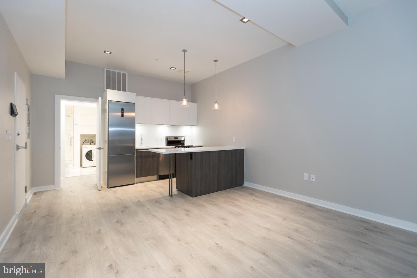 a kitchen with kitchen island a refrigerator and a sink