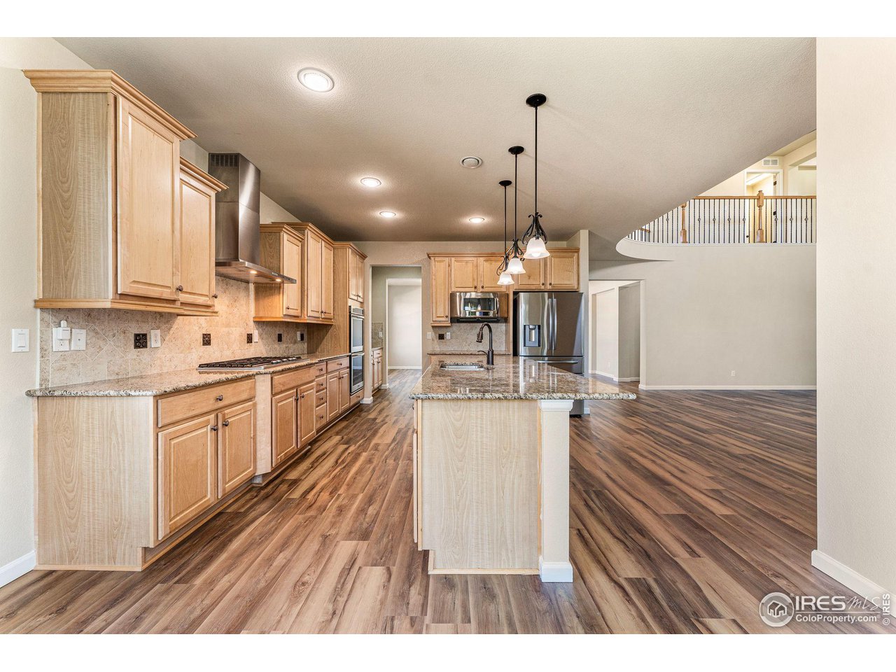 5101 Eagan Circle Longmont, CO 80503 - Photo 10 of 39 a open kitchen with kitchen island a stove a sink dishwasher and a refrigerator with wooden floor