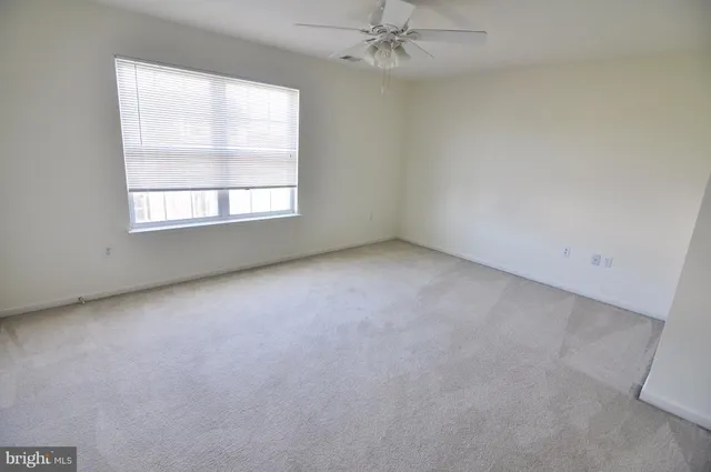 an empty room with a window and a fan