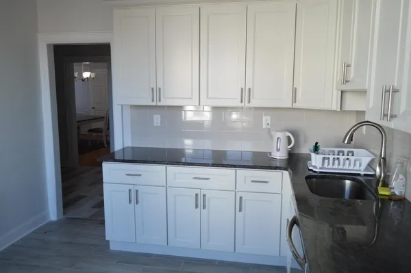 a kitchen with granite countertop white cabinets and sink