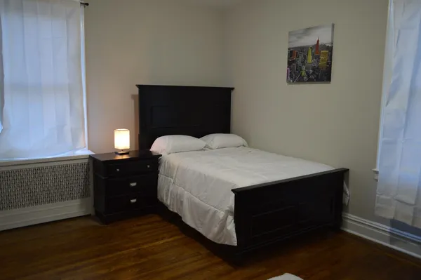 a bedroom with a bed and a lamp on the dresser