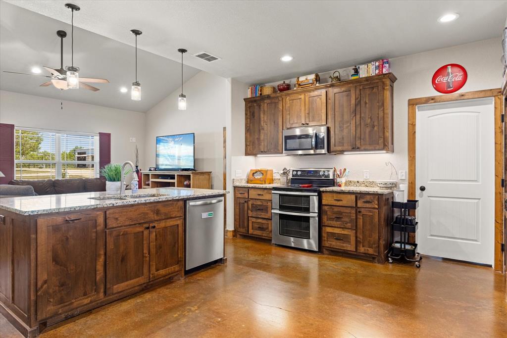 3761 County Road 149 Bluff Dale, TX 76433 - Photo 10 of 37 a kitchen with granite countertop stainless steel appliances and wooden cabinets