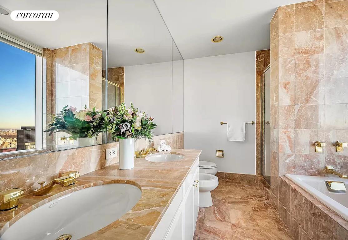 845 United Nations Plaza, Unit 42E Manhattan, NY 10017 - Photo 6 of 10 a bathroom with a granite countertop sink and a large mirror