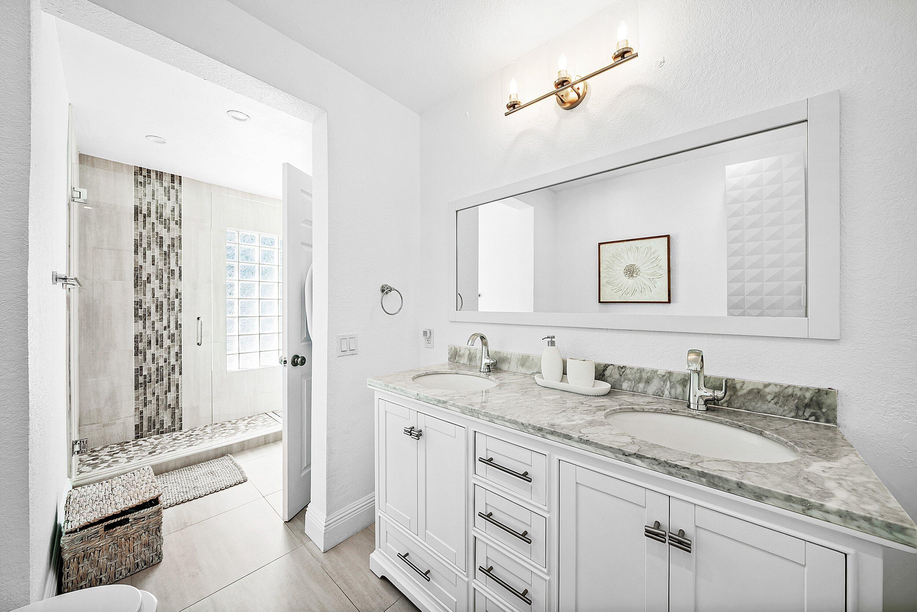 124 Oregon Lane Boca Raton, FL 33487 - Photo 23 of 41 a bathroom with a granite countertop sink a mirror a vanity and a bathtub