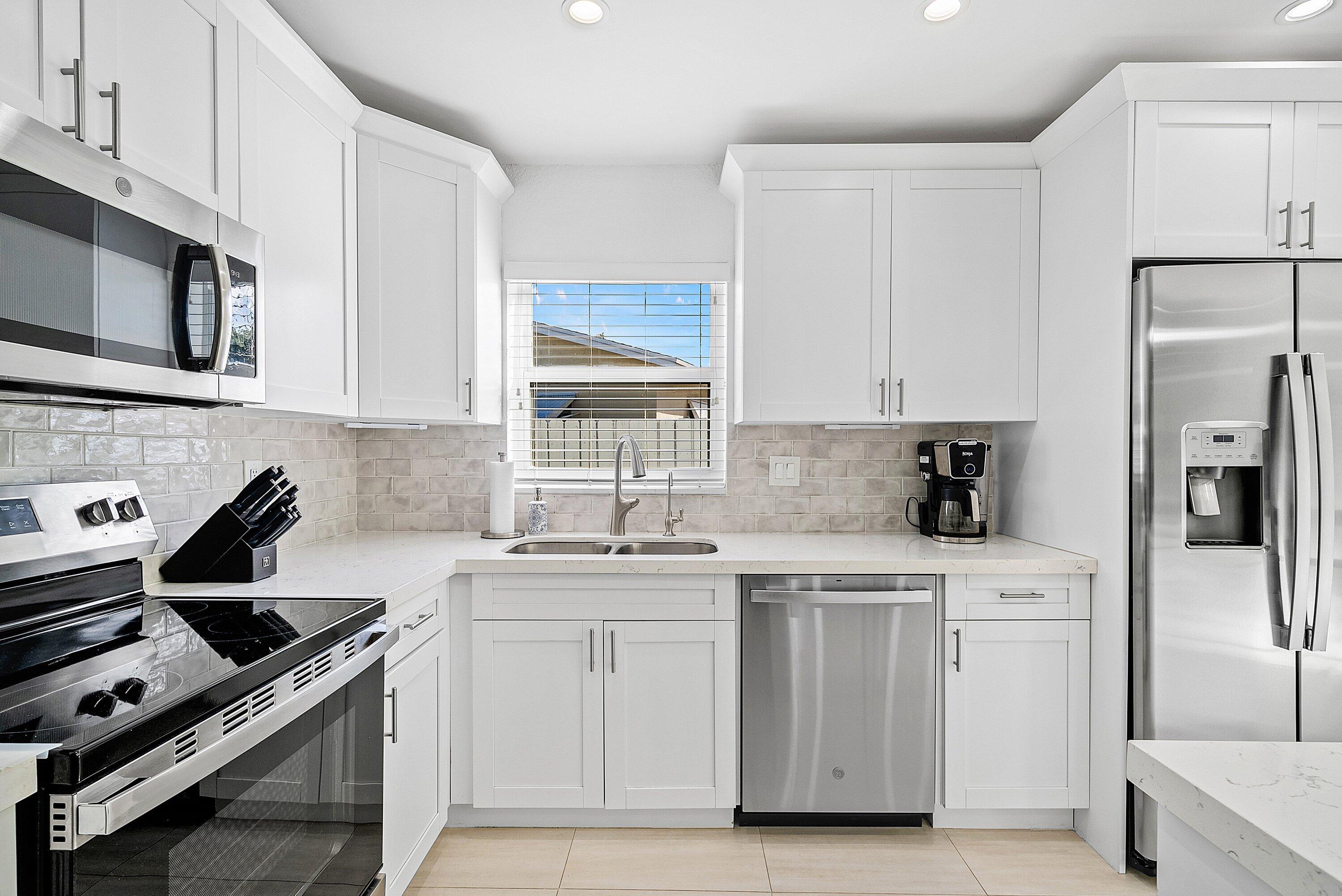 124 Oregon Lane Boca Raton, FL 33487 - Photo 7 of 41 a kitchen with white cabinets stainless steel appliances and sink