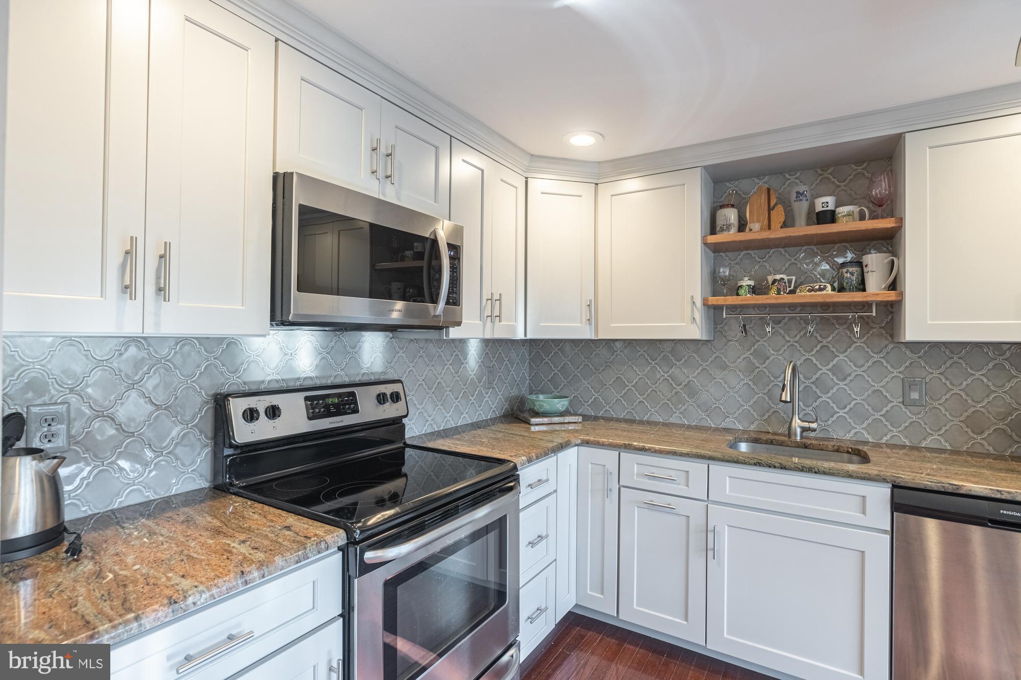 a kitchen with stainless steel appliances granite countertop grey cabinets a stove a sink and dishwasher