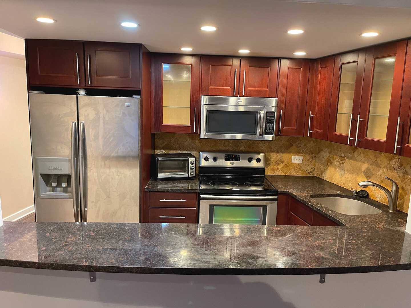 300 North State Street, Unit 2427 Chicago, IL 60654 - Photo 3 of 9 a kitchen with stainless steel appliances granite countertop a refrigerator a stove and a sink with wooden cabinets