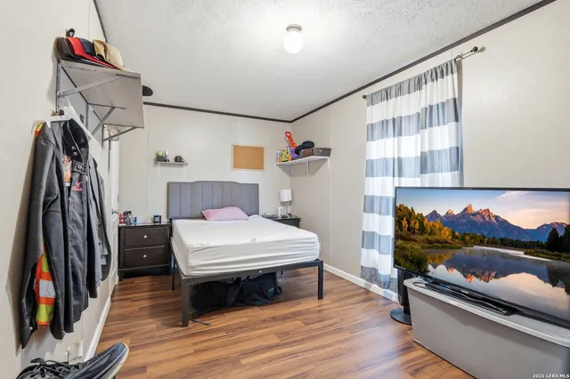 a bedroom with a bed and a flat tv screen on the dresser