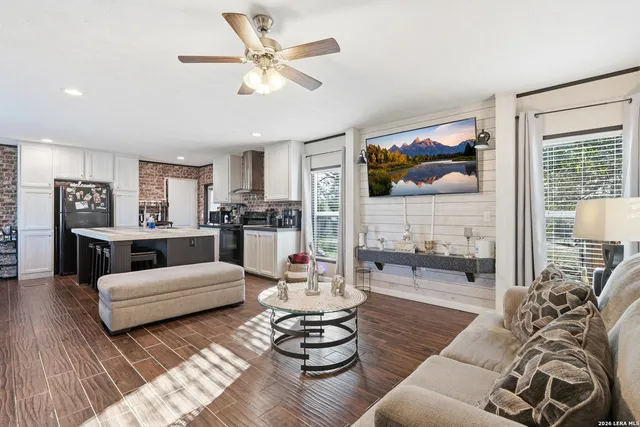 a living room with furniture kitchen view and a large window