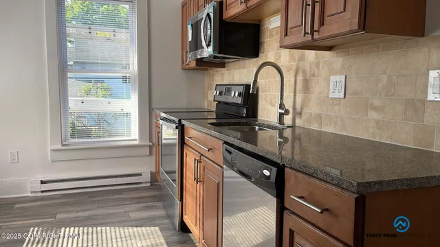 a kitchen with stainless steel appliances granite countertop a sink a stove and a microwave