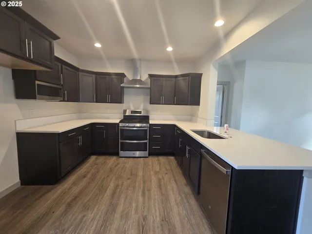 a large kitchen with stainless steel appliances a large counter top a stove a sink dishwasher and a microwave oven on the wall