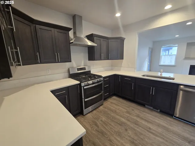 a kitchen with stainless steel appliances a sink a stove a refrigerator and cabinets