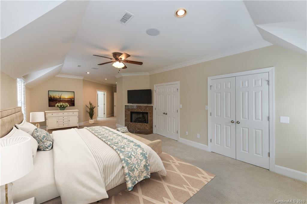 919 Colville Road Charlotte, NC 28207 - Photo 13 of 38 a spacious bedroom with a large bed a chandelier and a television