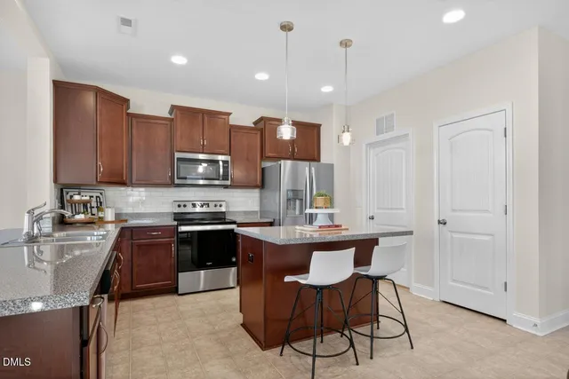 a kitchen with kitchen island granite countertop a sink cabinets and stainless steel appliances