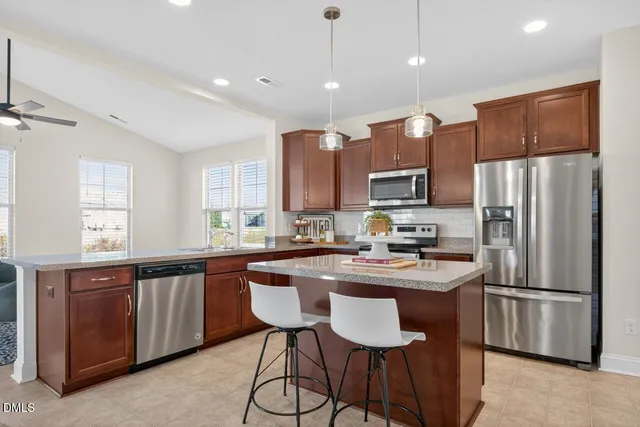 a kitchen with stainless steel appliances a sink a stove a refrigerator cabinets and a center island
