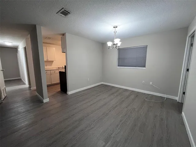 an empty room with wooden floor and chandelier