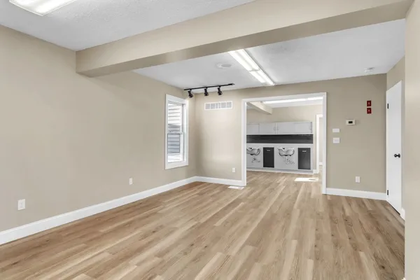 a view of an empty room with wooden floor and a window