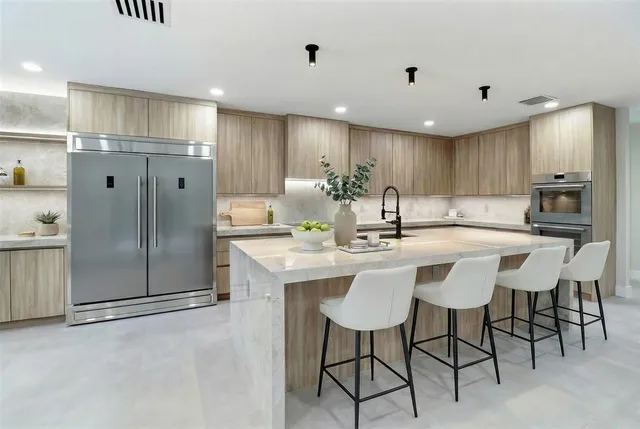 a kitchen with stainless steel appliances kitchen island granite countertop a refrigerator and a stove top oven