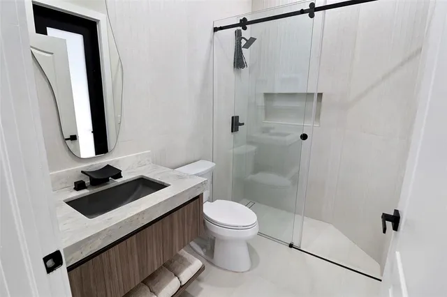 a bathroom with a sink a toilet a mirror and shower