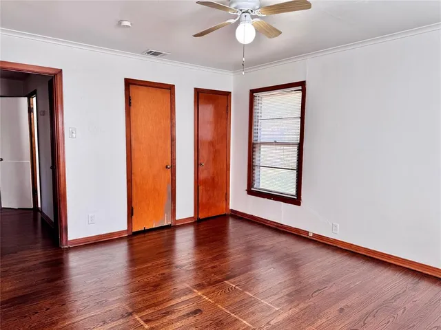 an empty room with wooden floor chandelier fan and windows
