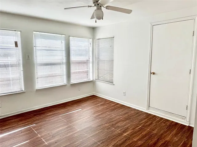 an empty room with wooden floor cabinet and windows