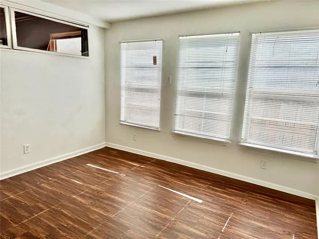 a view of an empty room with a window and wooden floor