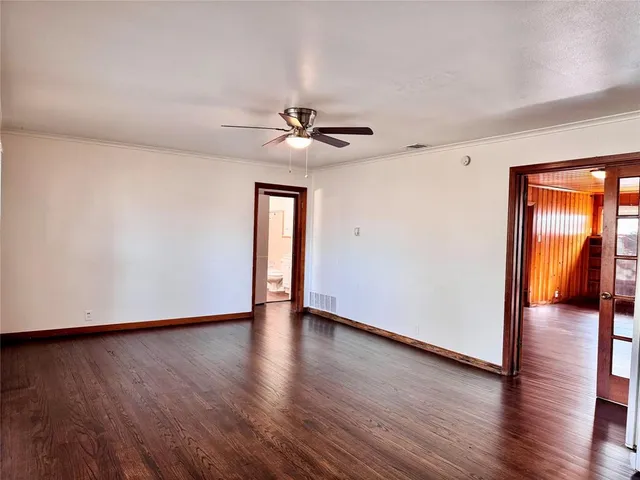 a view of an empty room with window and wooden floor