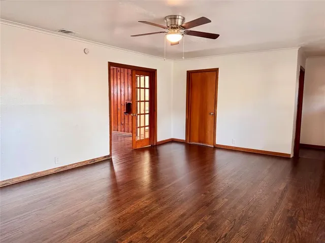 a view of an empty room with window and wooden floor